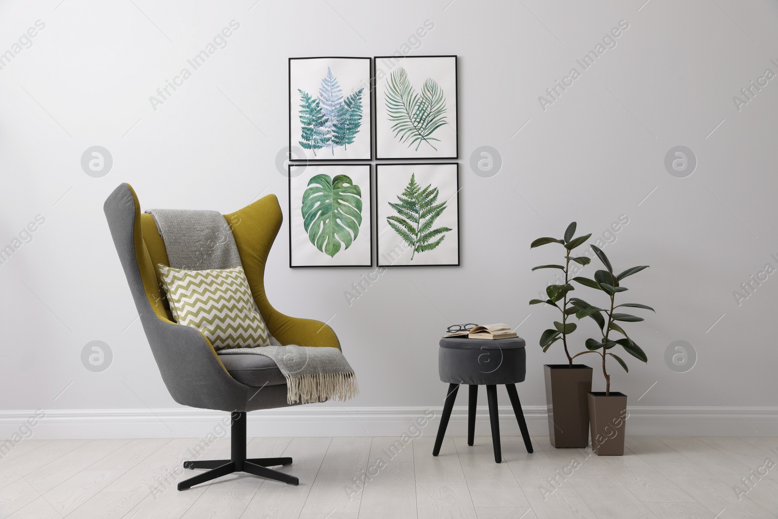 Photo of Stylish room interior with comfortable armchair and paintings of tropical leaves