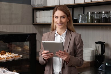 Happy business owner with tablet in bakery shop