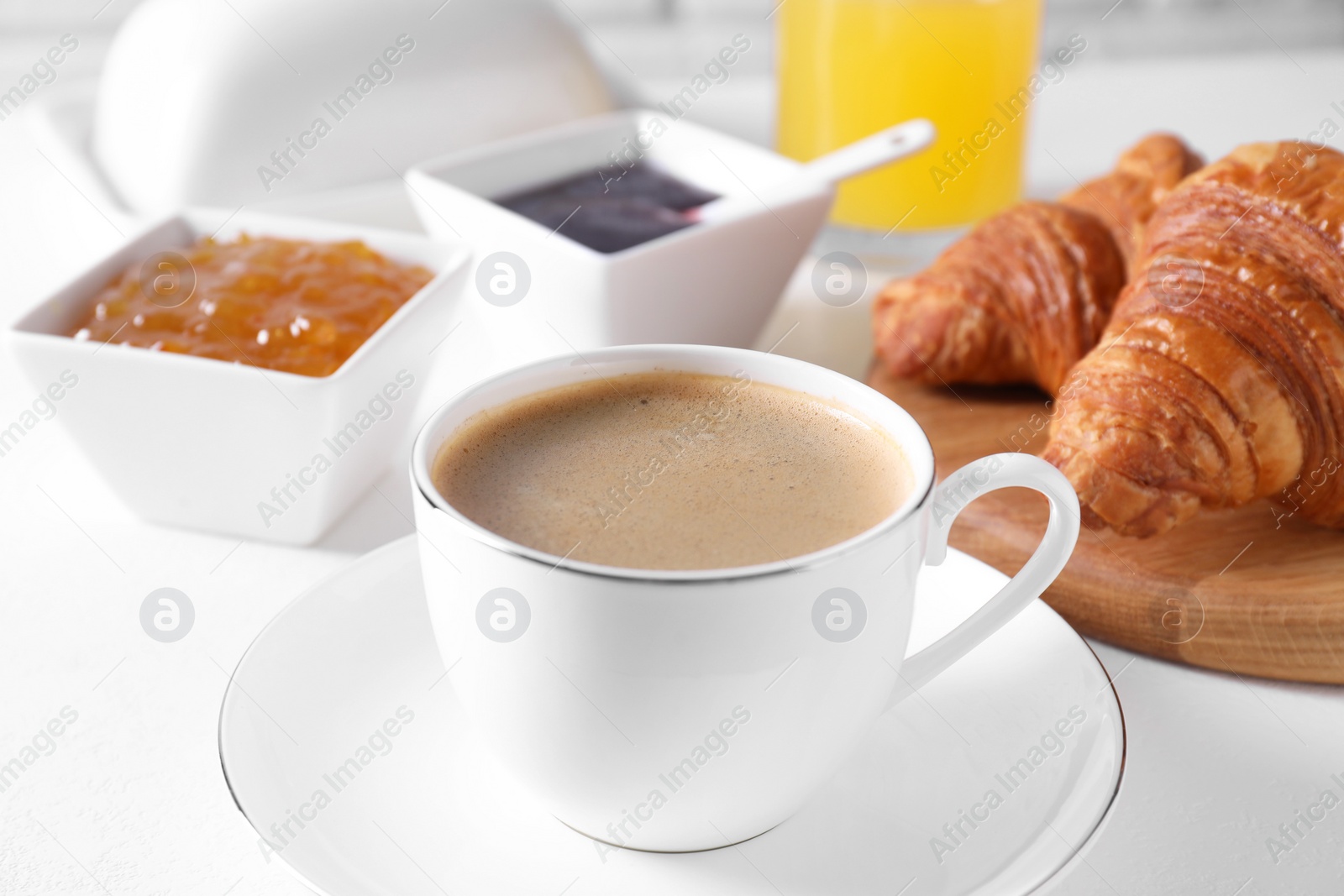 Photo of Fresh croissants, jams and coffee on white table, closeup. Tasty breakfast