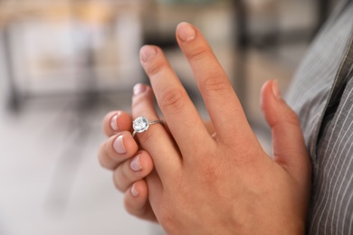 Woman taking off wedding ring indoors, closeup. Divorce concept