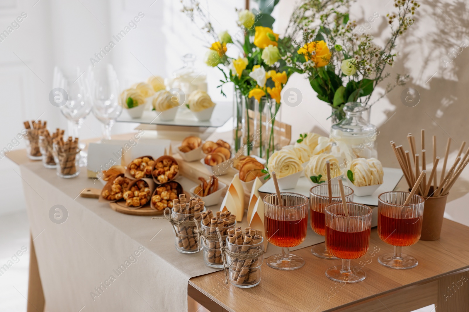 Photo of Delicious treats and glasses of drink on wooden table in room. Sweet buffet