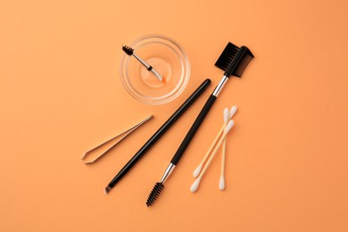 Photo of Flat lay composition with eyebrow professional tools on orange background