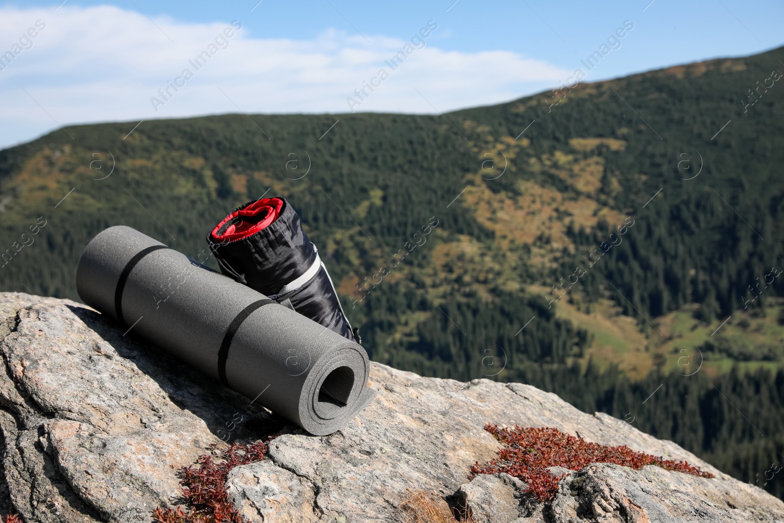 Photo of Sleeping bag and camping mat on mountain peak, space for text