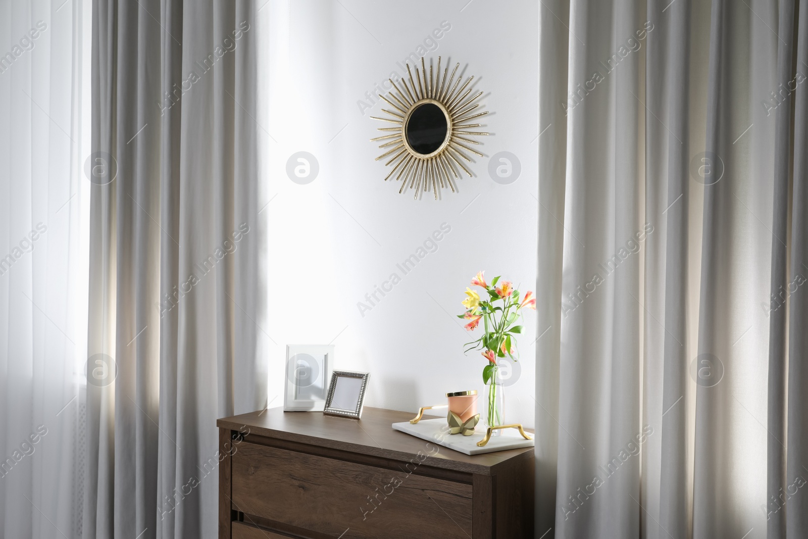 Photo of Stylish room interior with wooden chest of drawers and beautiful decor elements