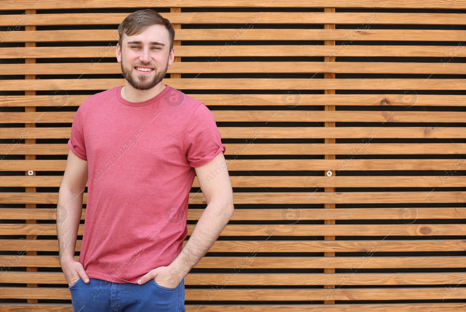 Photo of Portrait of young man in stylish outfit near wooden wall