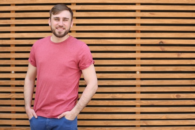 Portrait of young man in stylish outfit near wooden wall