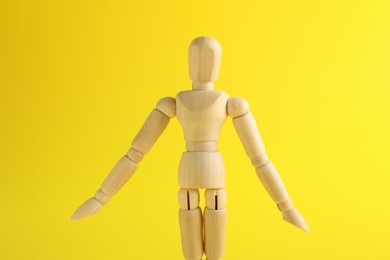 Wooden human model on yellow background. Mini mannequin