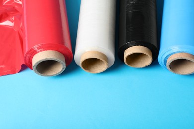 Photo of Rolls of different plastic stretch wrap on light blue background. Space for text