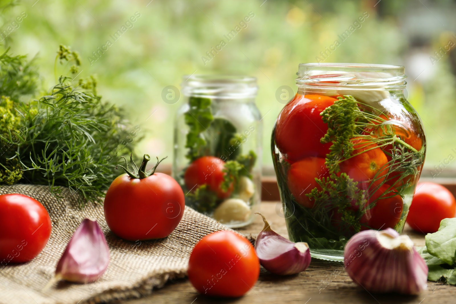 Photo of Glass jars, fresh vegetables and herbs on wooden table indoors. Pickling recipe