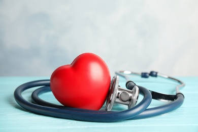 Photo of Stethoscope and red heart on wooden table. Cardiology concept
