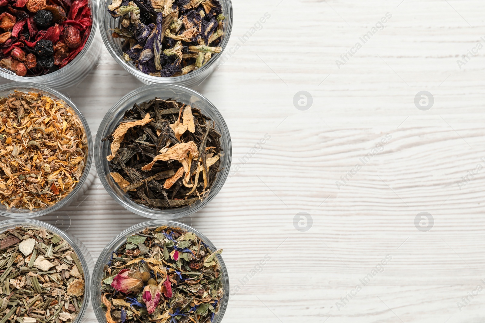 Photo of Flat lay composition with different dry teas on white wooden table. Space for text