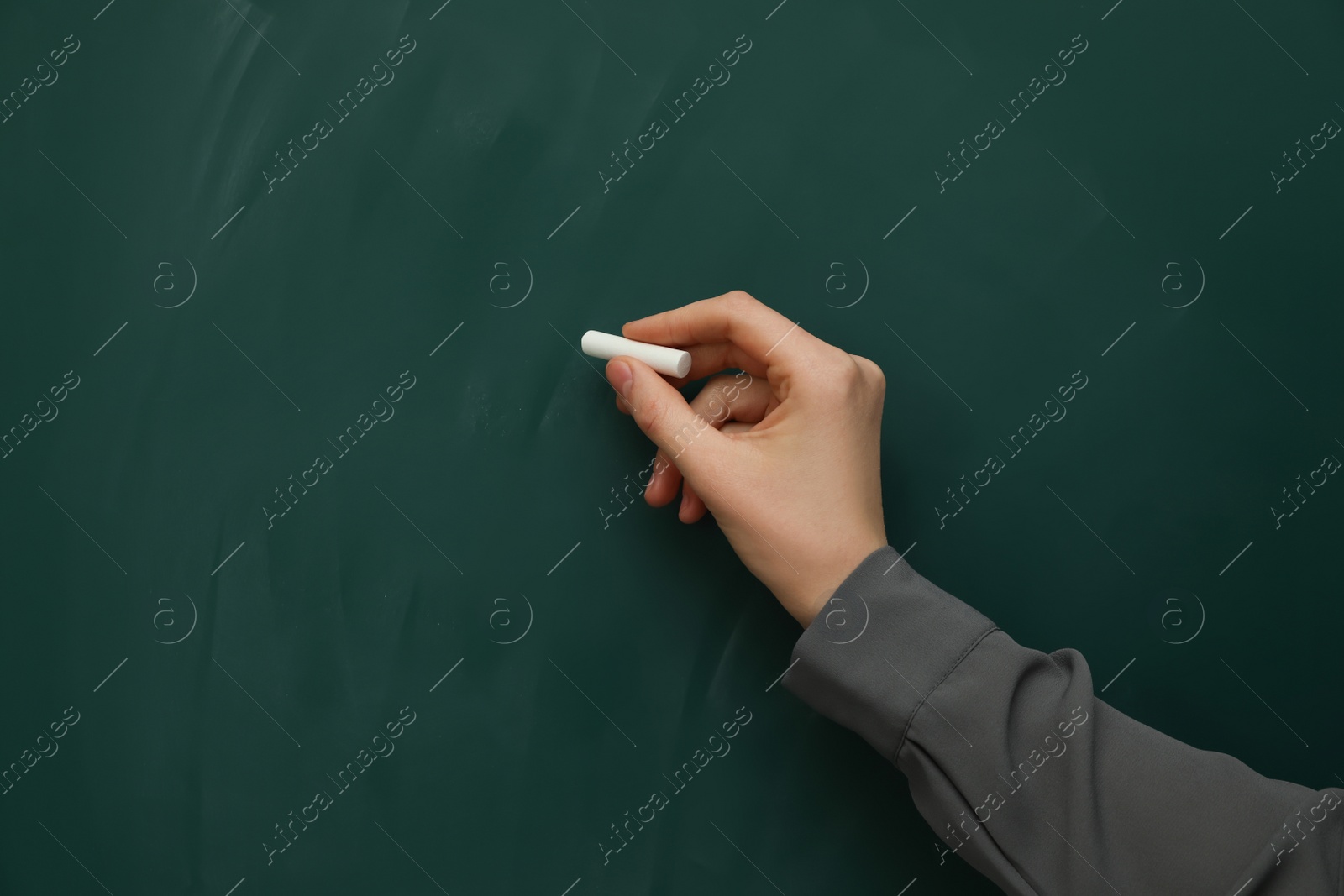 Photo of Woman with white chalk near green board, closeup. Space for text