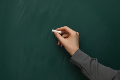 Woman with white chalk near green board, closeup. Space for text