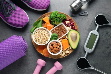 Photo of Plate with heart-healthy products and sports equipment on grey background, flat lay