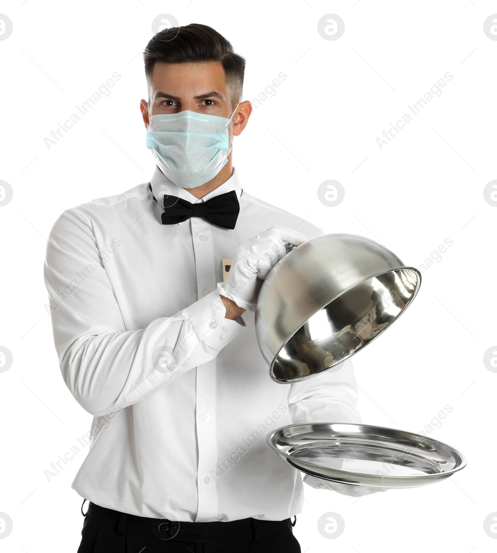 Photo of Waiter in medical face mask holding tray with lid on white background