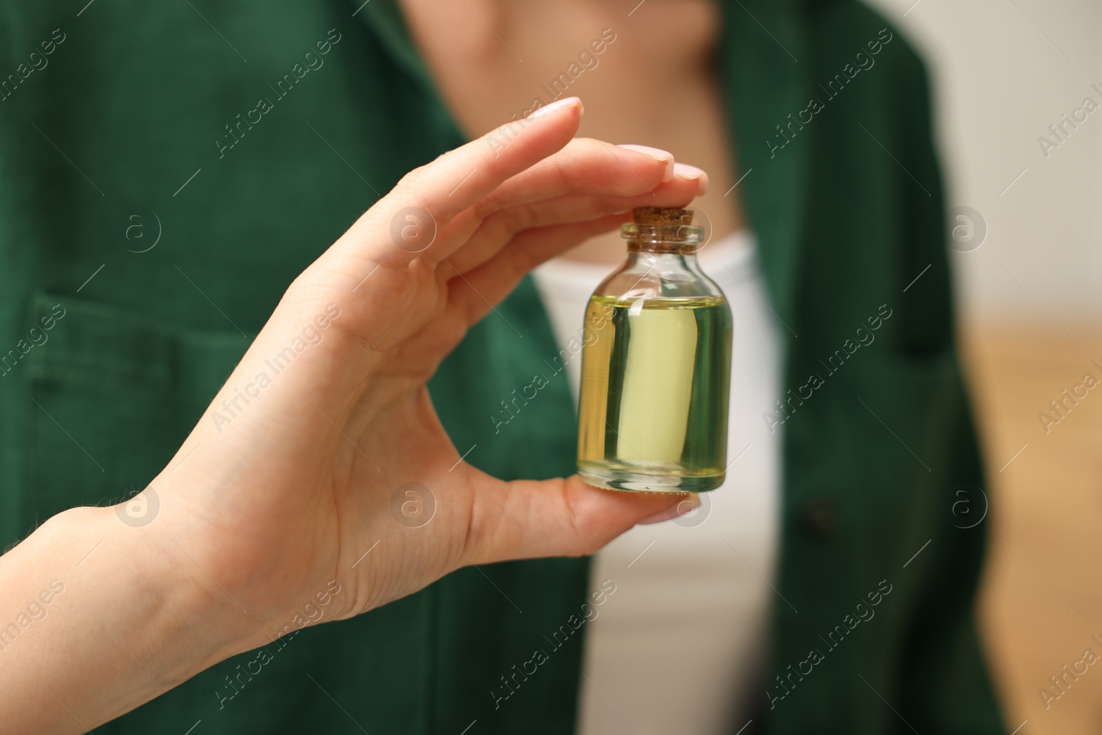 Photo of Aromatherapy. Woman with bottle of essential oil on light background, closeup