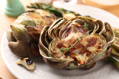 Photo of Tasty grilled artichokes on white plate, closeup