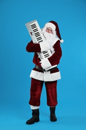 Photo of Santa Claus with synthesizer on blue background. Christmas music