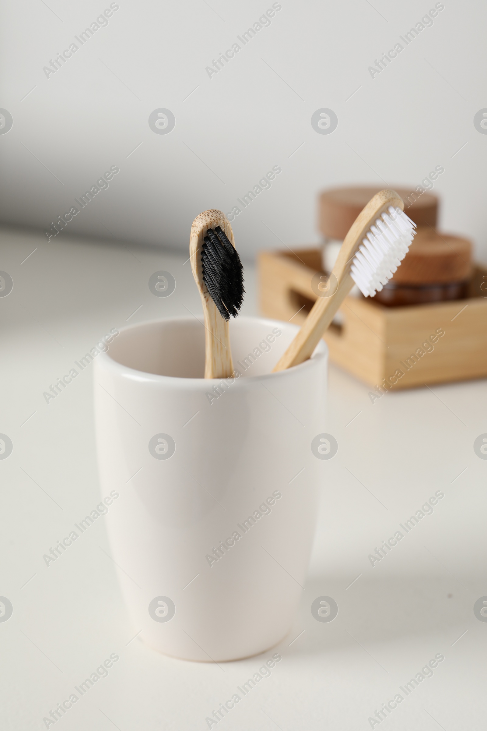 Photo of Bamboo toothbrushes in holder on white countertop