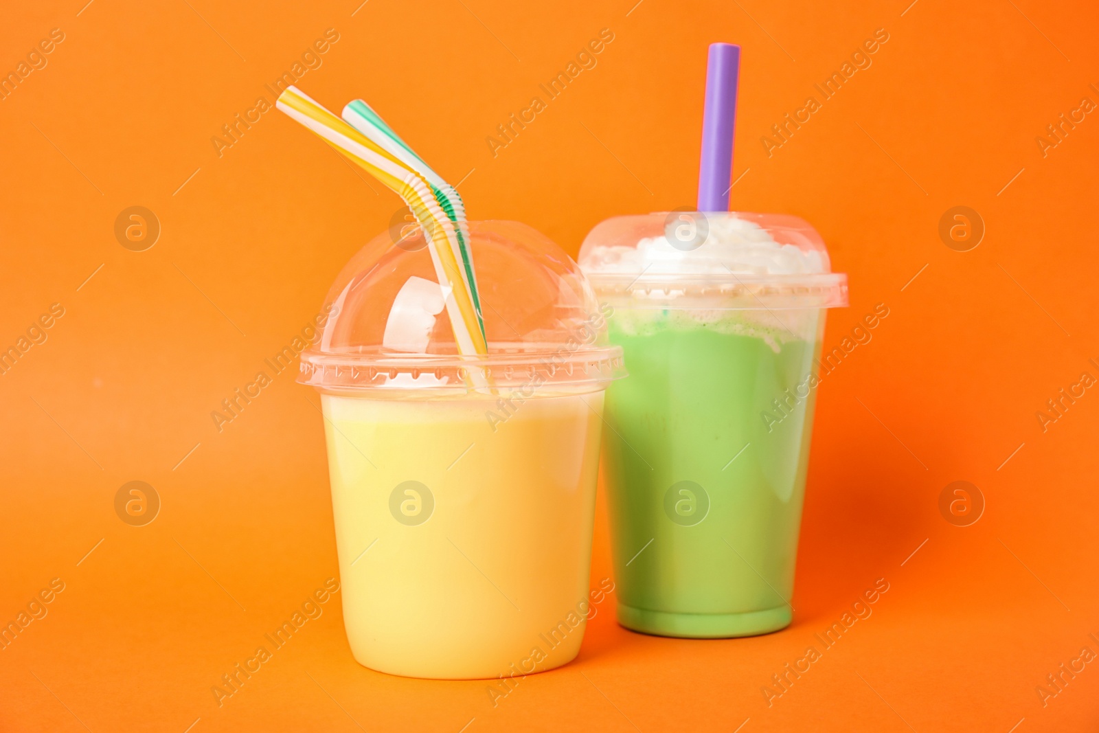 Photo of Plastic cups of tasty milk shakes on color background