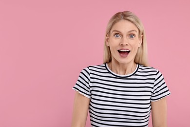 Photo of Portrait of surprised woman on pink background, space for text