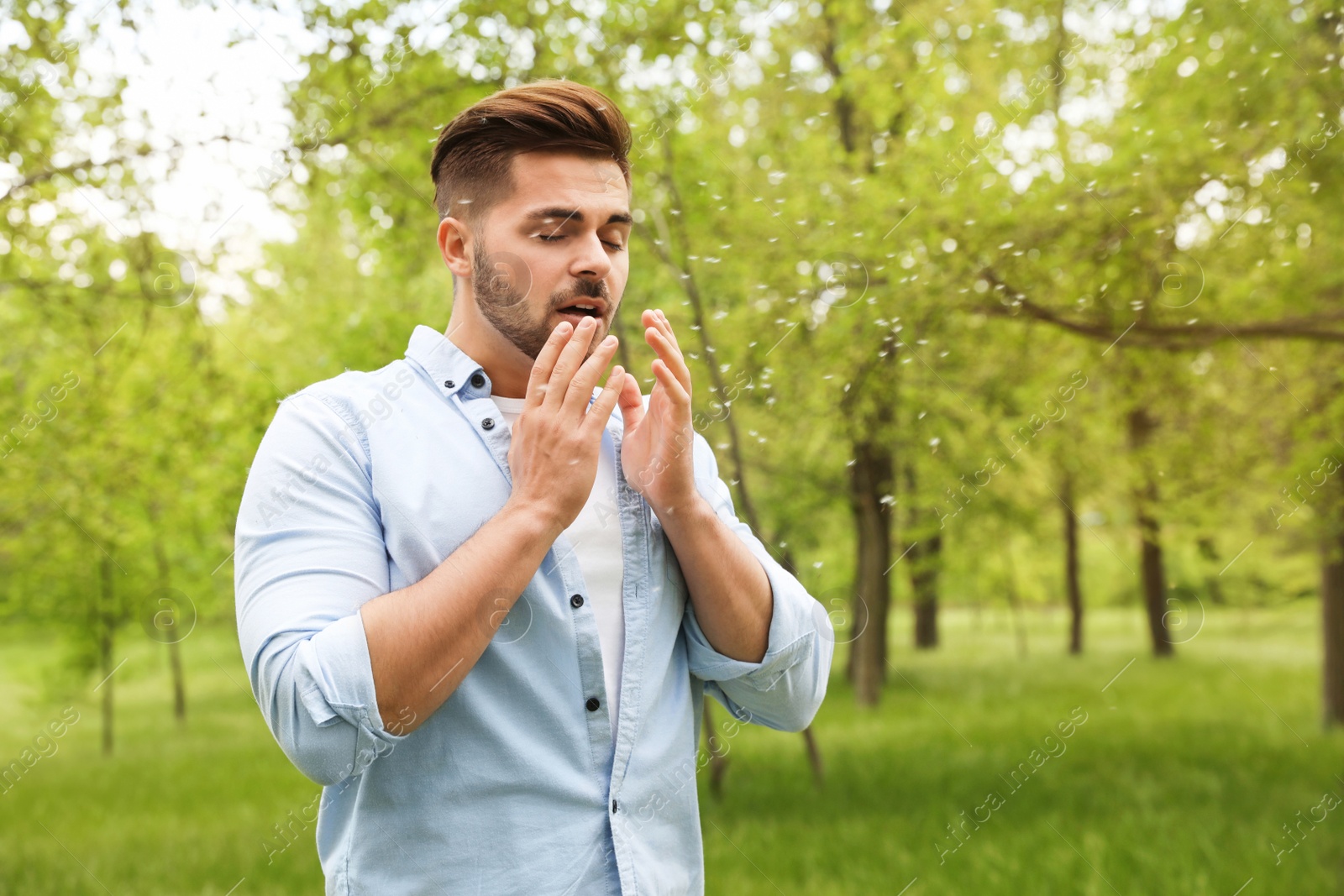 Photo of Young man suffering from seasonal allergy outdoors, space for text