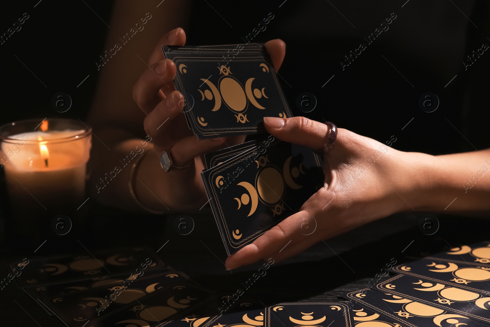 Photo of Soothsayer shuffling tarot cards at table in darkness. Fortune telling