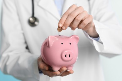 Photo of Doctor putting coin into piggy bank in hospital, closeup
