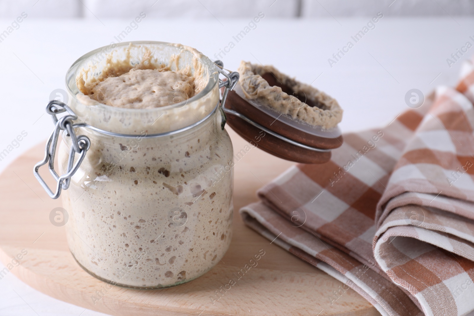 Photo of Sourdough starter in glass jar on table, closeup