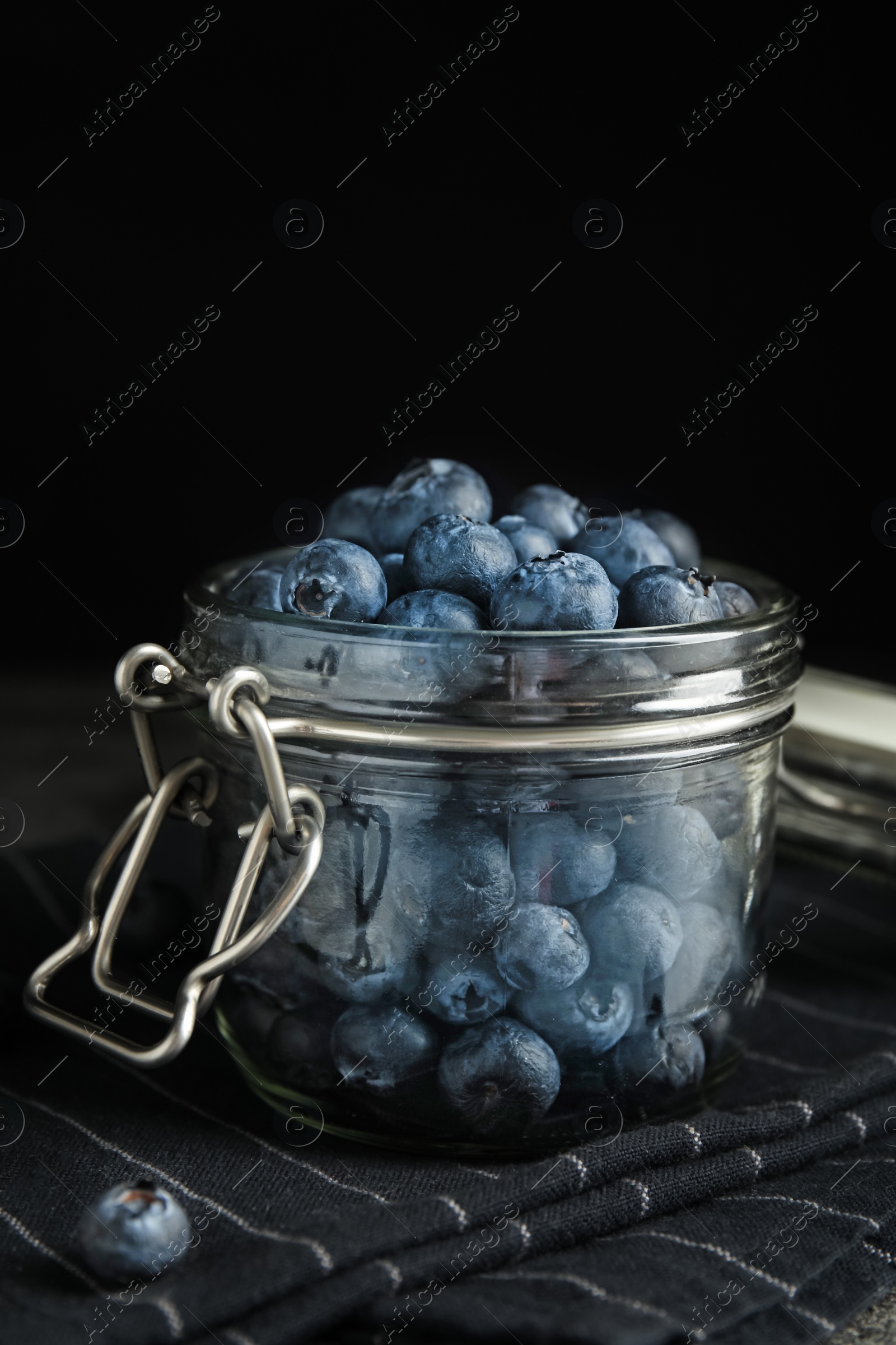 Photo of Tasty ripe blueberries in glass jar on table