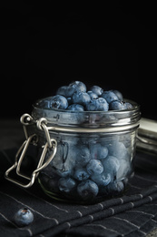 Photo of Tasty ripe blueberries in glass jar on table