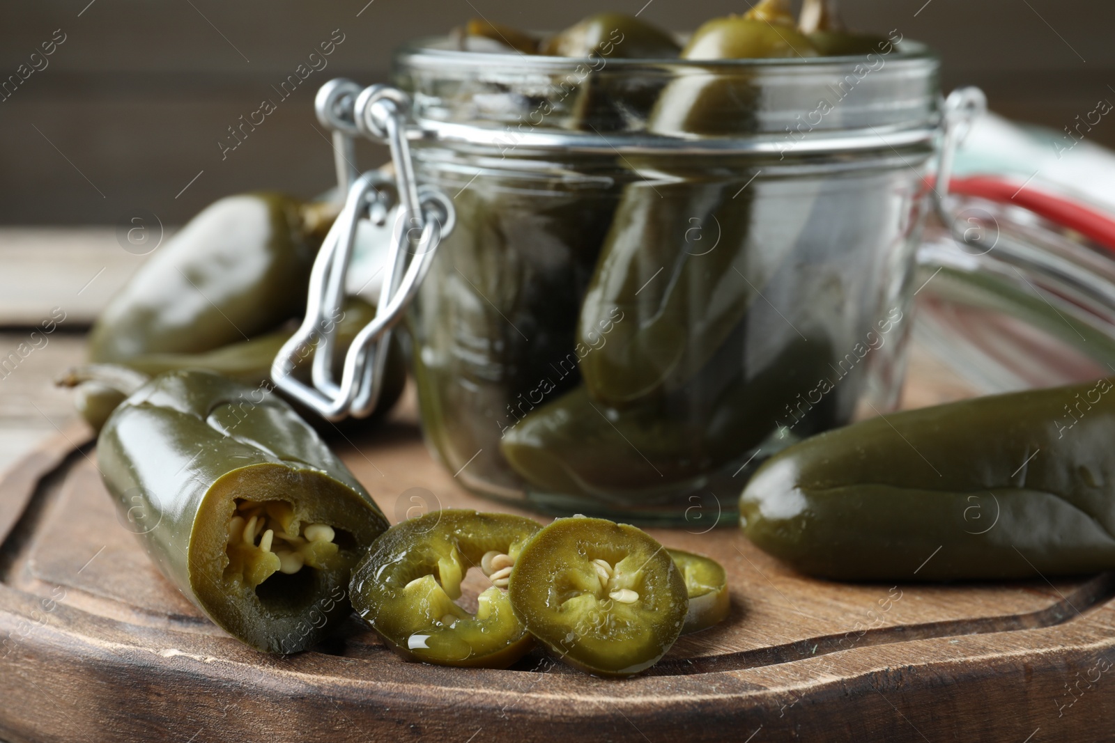 Photo of Pickled green jalapeno peppers on wooden board, closeup