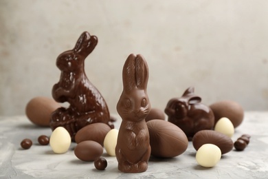 Photo of Chocolate Easter bunnies and eggs on light grey table
