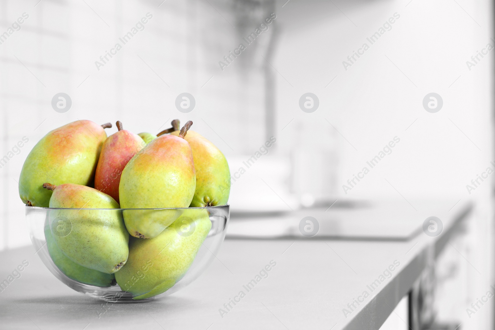 Photo of Fresh ripe pears on grey countertop in kitchen. Space for text