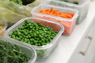 Plastic and glass containers with different fresh products on white countertop, closeup