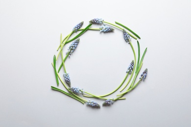 Photo of Frame made of spring muscari flowers on color background, top view with space for text