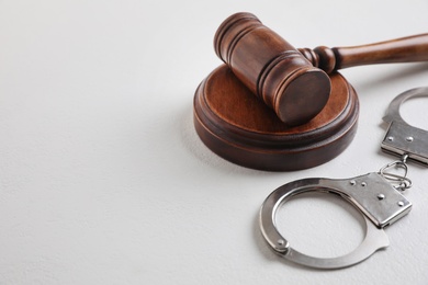 Photo of Gavel and handcuffs on white table, space for text. Criminal law