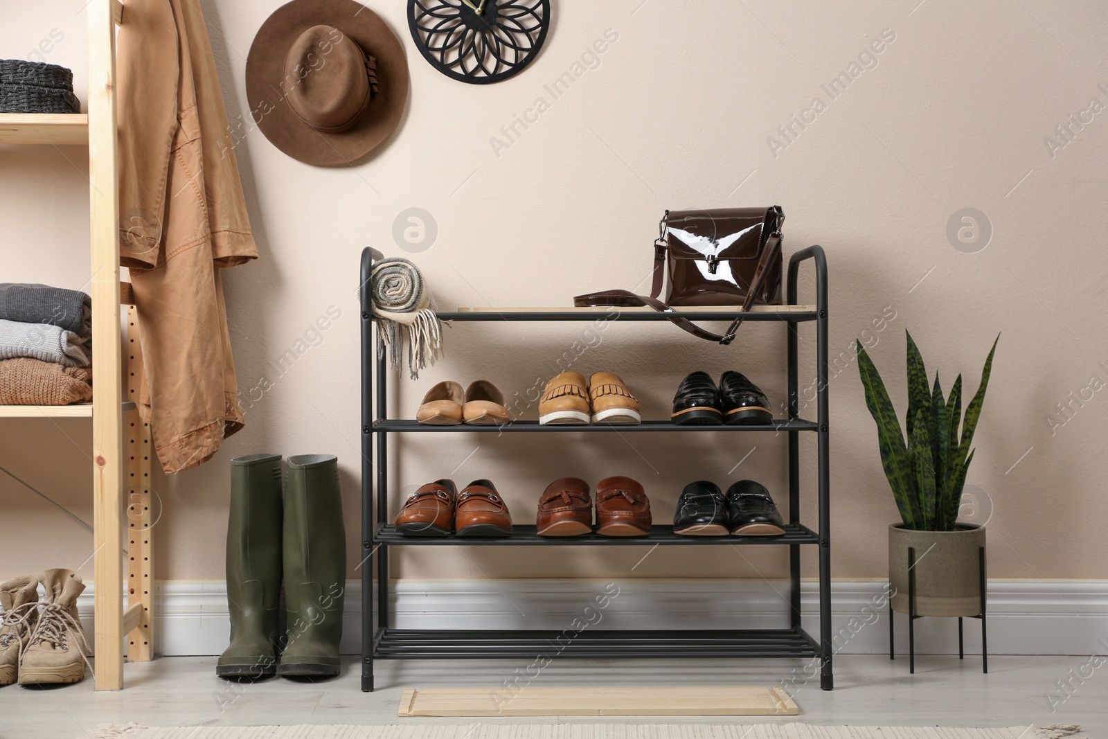 Photo of Rack with different shoes near beige wall in room