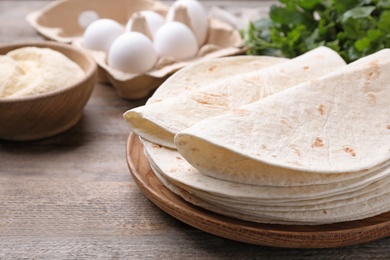 Photo of Wooden plate with corn tortillas on table, space for text. Unleavened bread