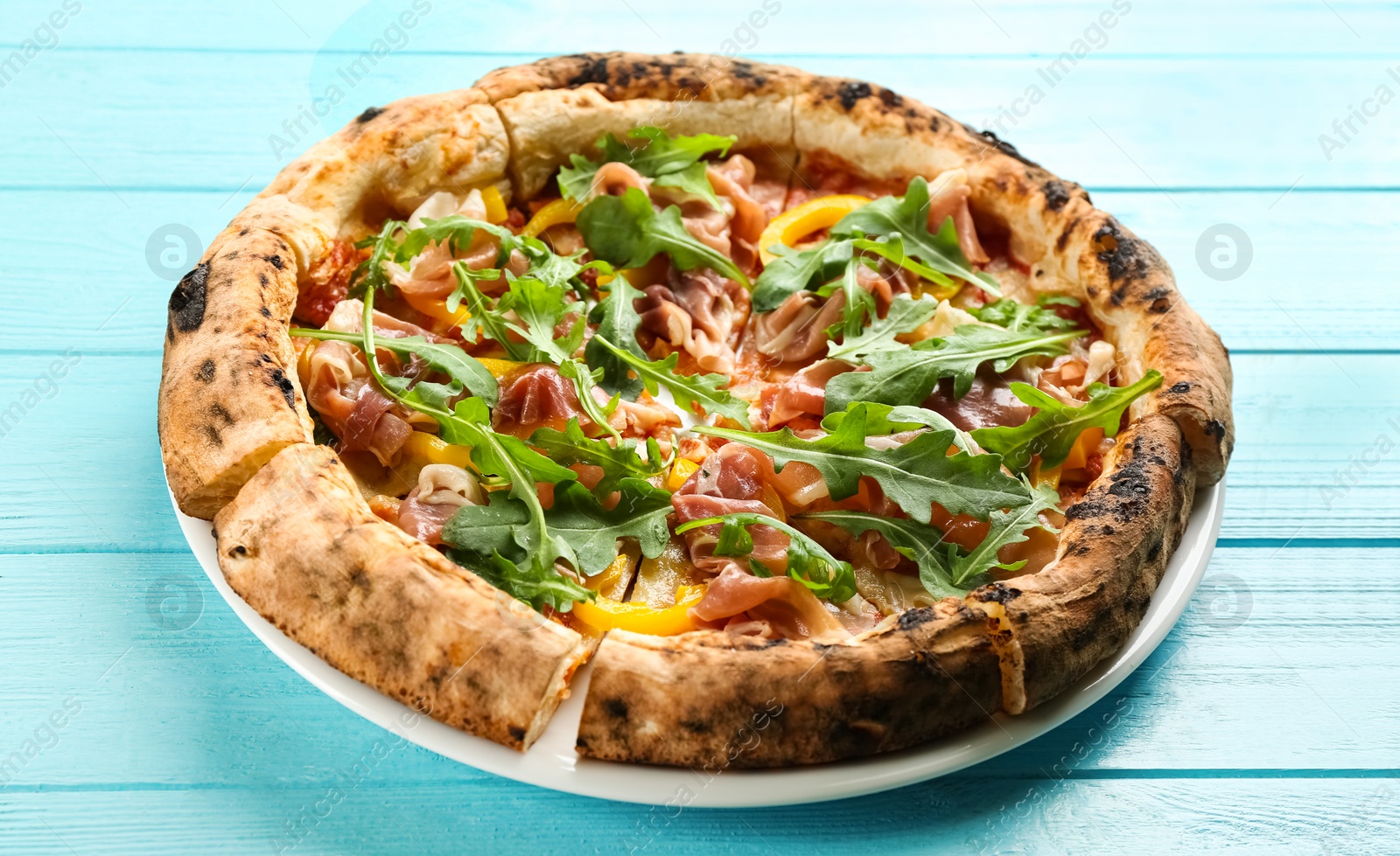 Photo of Tasty pizza with meat and arugula on light blue wooden table, closeup