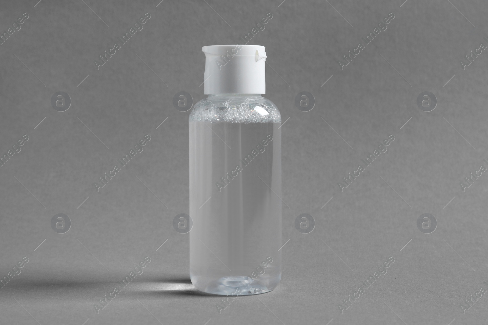 Photo of Transparent bottle with cosmetic product on grey background