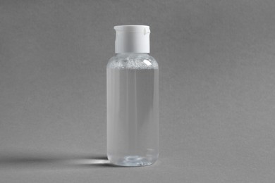 Photo of Transparent bottle with cosmetic product on grey background
