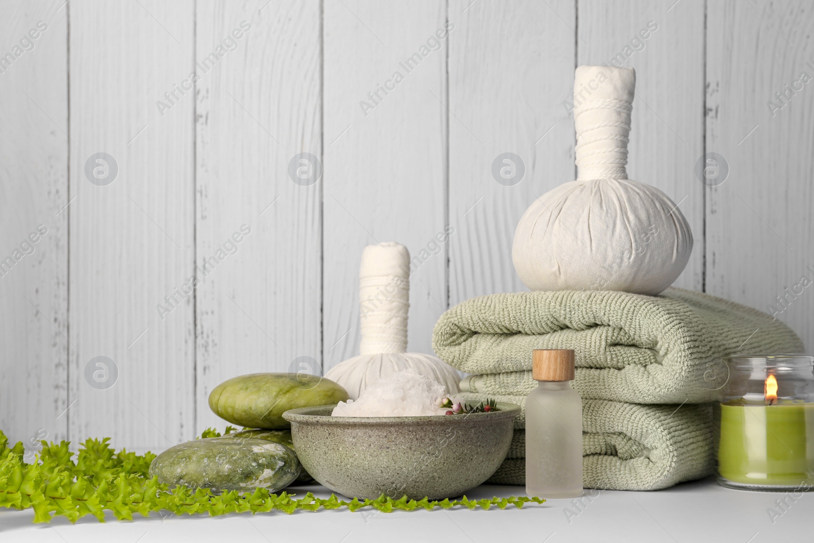 Photo of Composition with different spa products and candle on white table against wooden background. Space for text