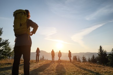 Tourists with backpacks in mountains on sunset, back view