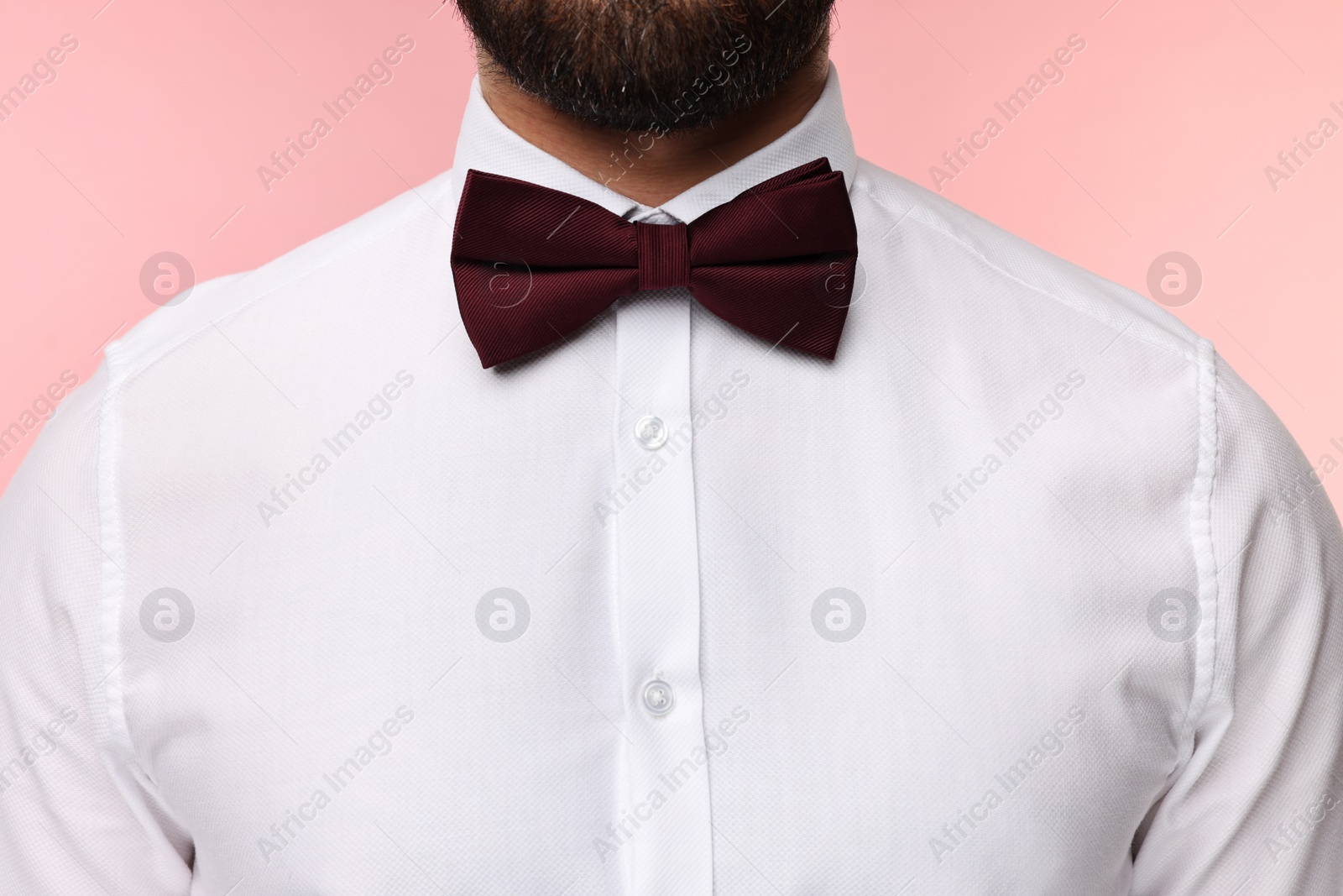 Photo of Man in shirt and bow tie on pink background, closeup