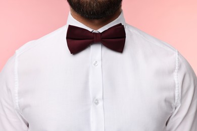 Man in shirt and bow tie on pink background, closeup