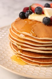 Photo of Delicious pancakes with fresh berries, butter and honey on table, closeup