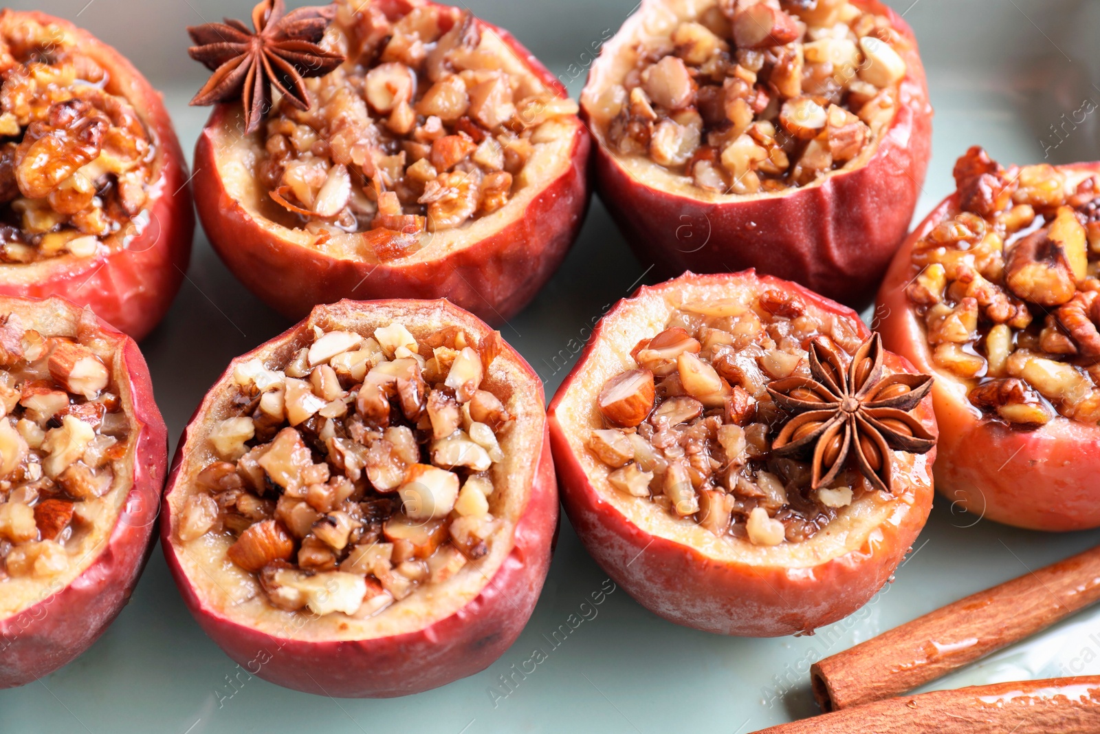 Photo of Tasty baked apples with nuts, honey and spices in dish, closeup