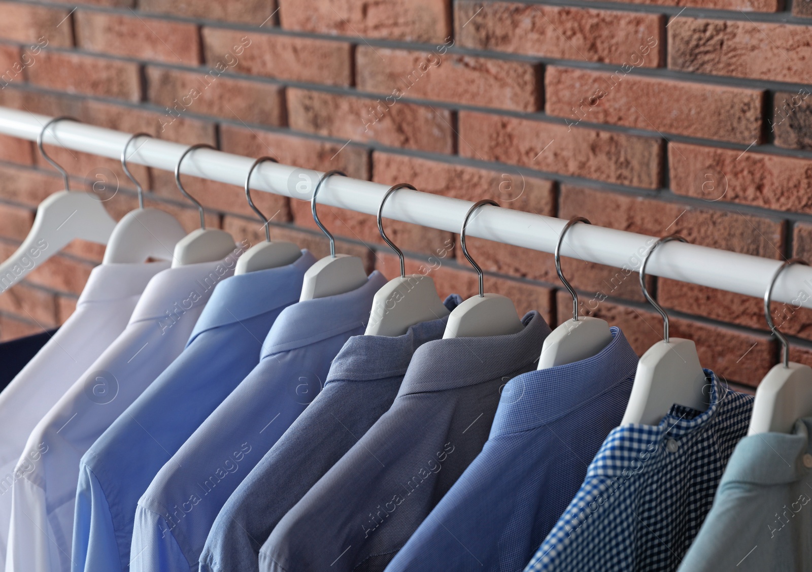 Photo of Wardrobe rack with men's clothes near brick wall