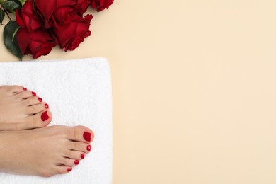 Photo of Woman with stylish red toenails after pedicure procedure and rose flowers on beige background, top view. Space for text